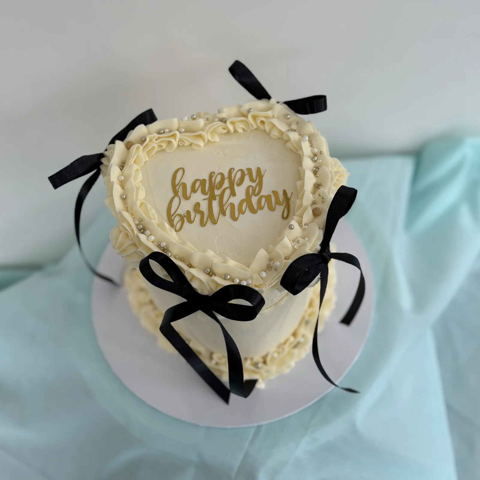 An elegant heart-shaped birthday cake with black bows