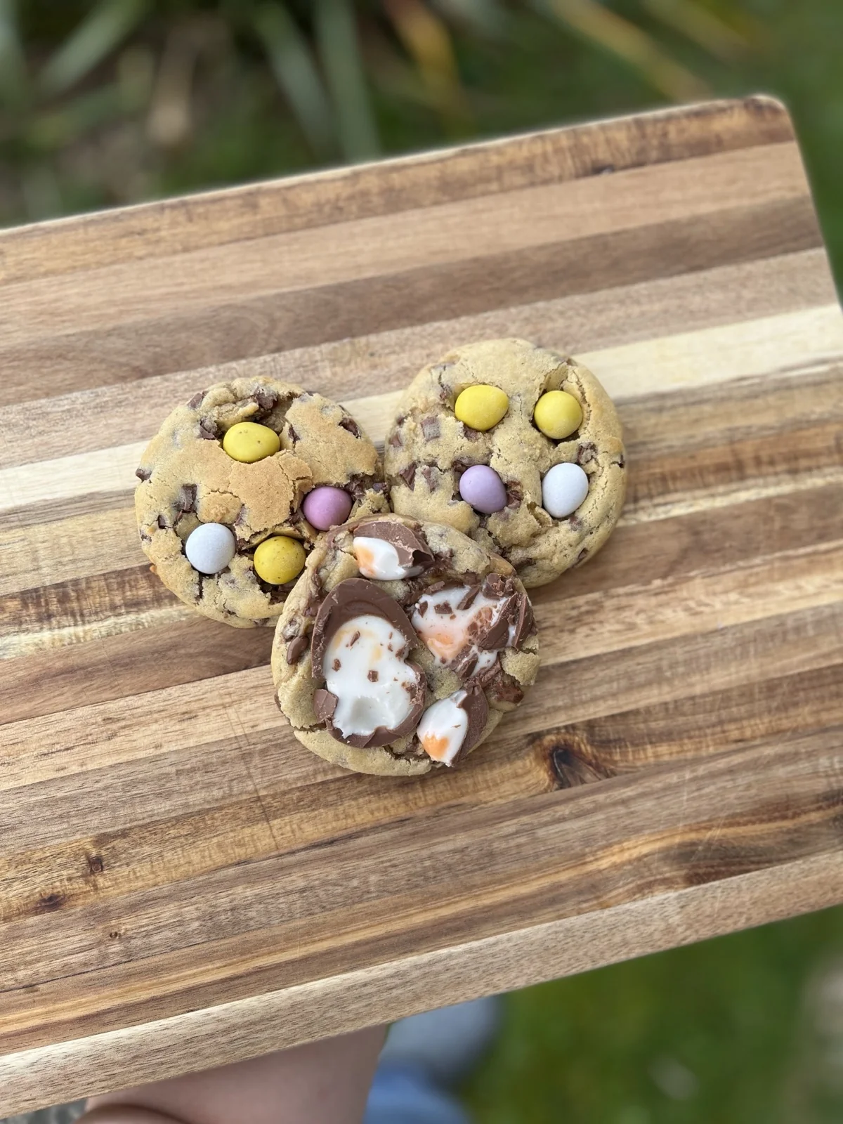 Creme egg and mini egg cookies on a wooden board